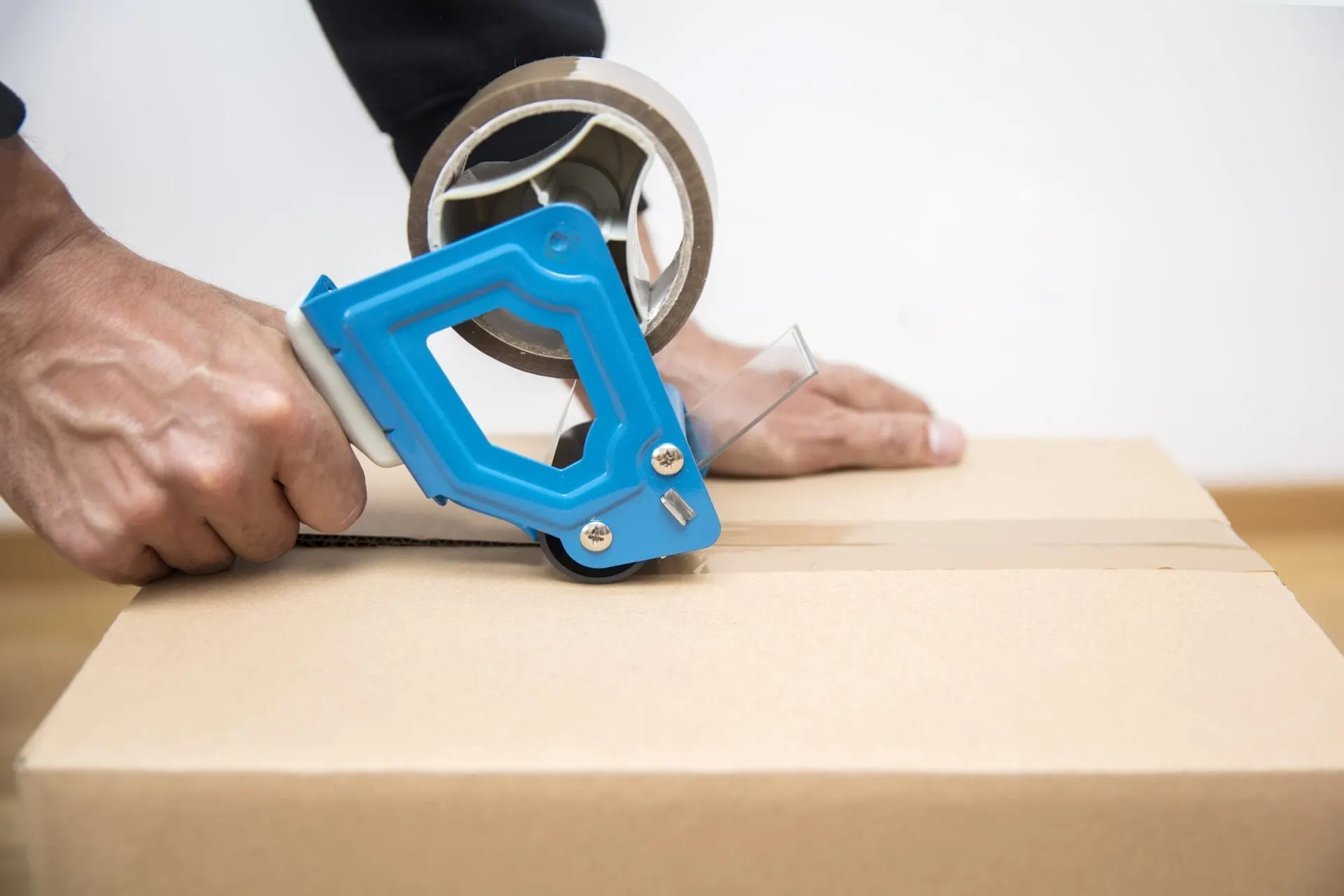 Hands sealing a moving box with packing tape